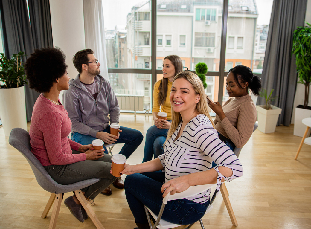 Reunión de trabajo en oficina de Sevilla, empleados sonrientes aplicando inteligencia emocional con la ayuda de un coach.